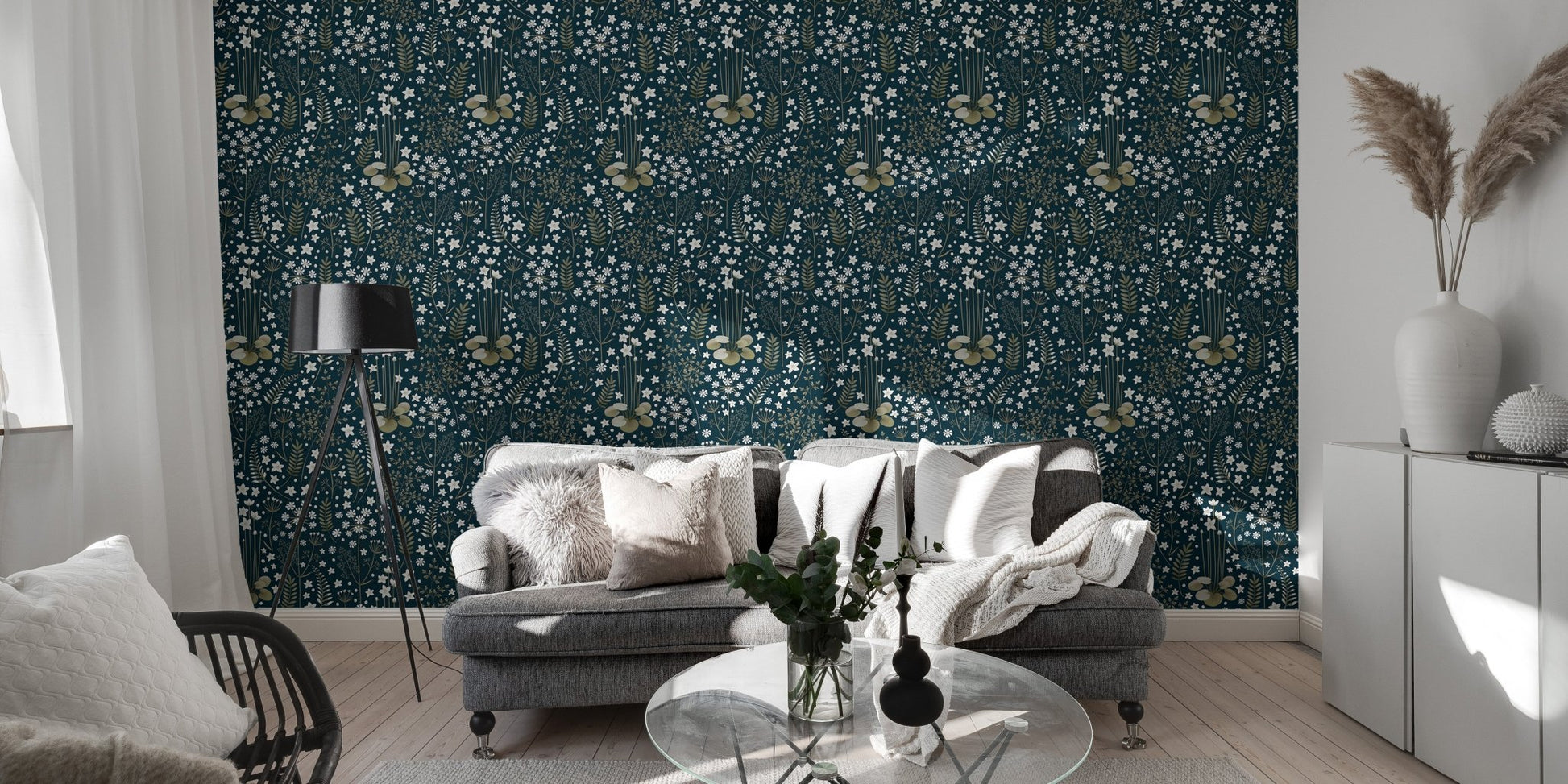 Navy blue leaf pattern wallpaper in a living room with a grey sofa and floor lamp.
