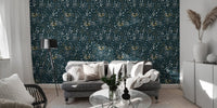 Navy blue leaf pattern wallpaper in a living room with a grey sofa and floor lamp.