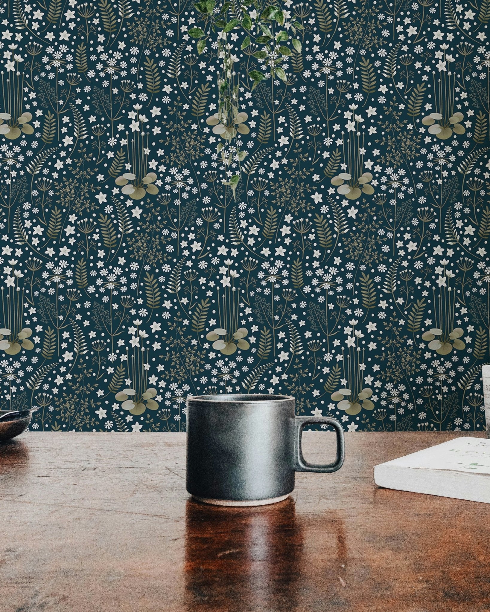 Detailed dark blue floral wallpaper behind a black coffee mug on a wooden table.