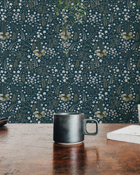 Detailed dark blue floral wallpaper behind a black coffee mug on a wooden table.