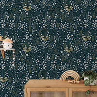 Botanical leaves wallpaper behind a wooden cabinet with small decor items.
