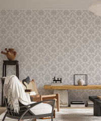 Classic damask wallpaper in a modern living area with a wooden desk and black chair.