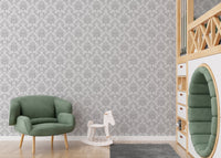 Gray damask wallpaper in a nursery with a green armchair and rocking horse.