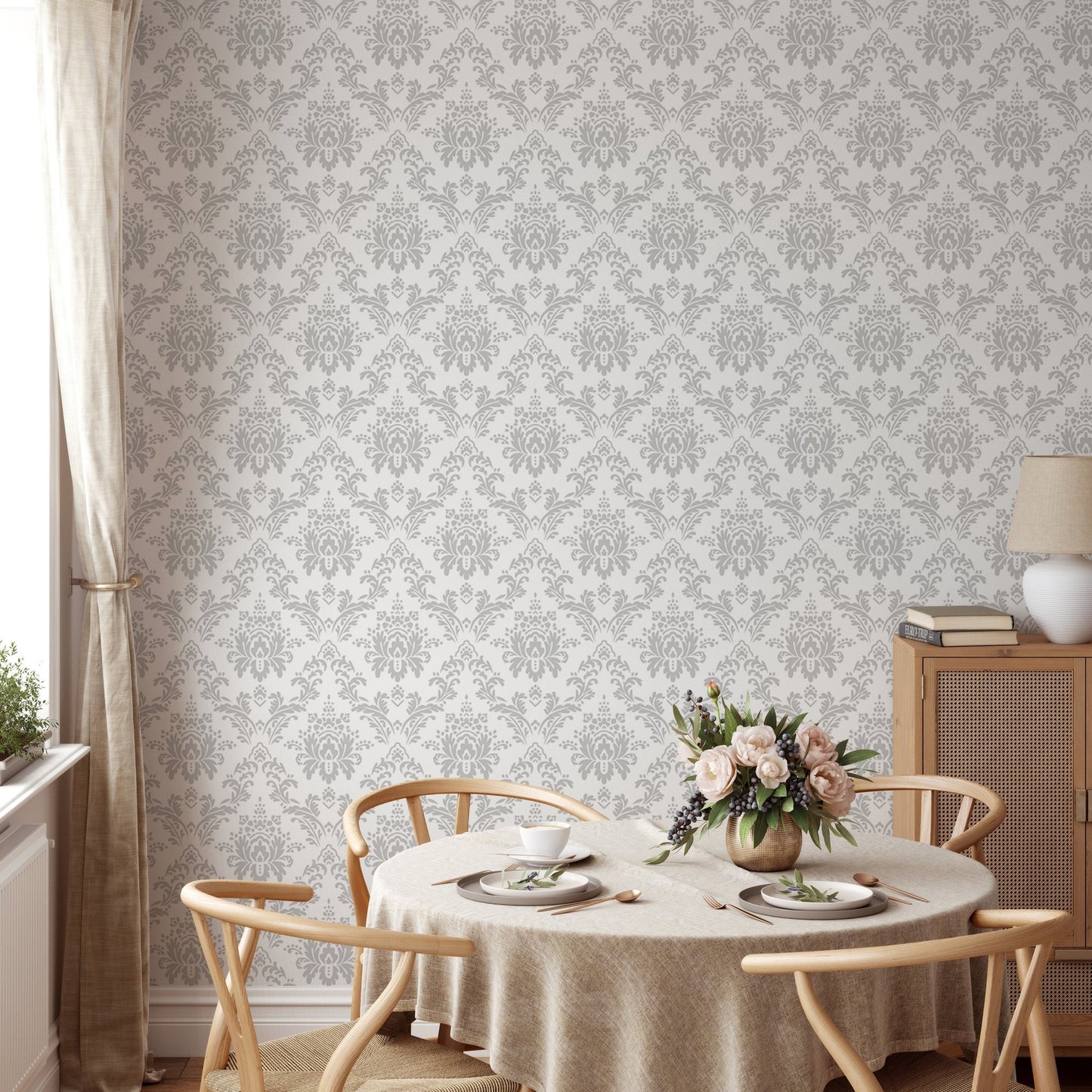 Gray floral wallpaper behind a round dining table with light wood chairs.
