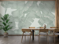 Banana leaf print wall mural in a dining room with wooden chairs and table.