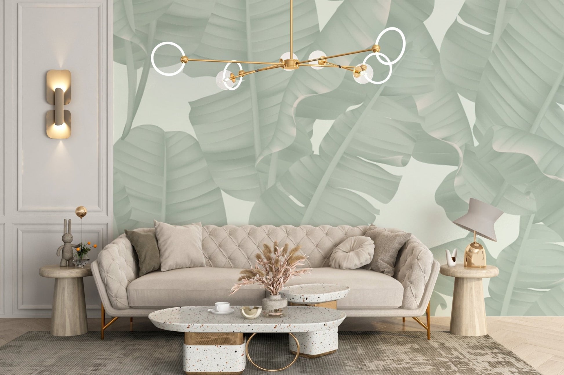 Green tropical foliage wall mural behind a beige sofa and gold pendant light in bright living room.