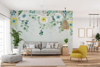 Floral wall mural in a bright living area with a grey sofa and yellow chair.