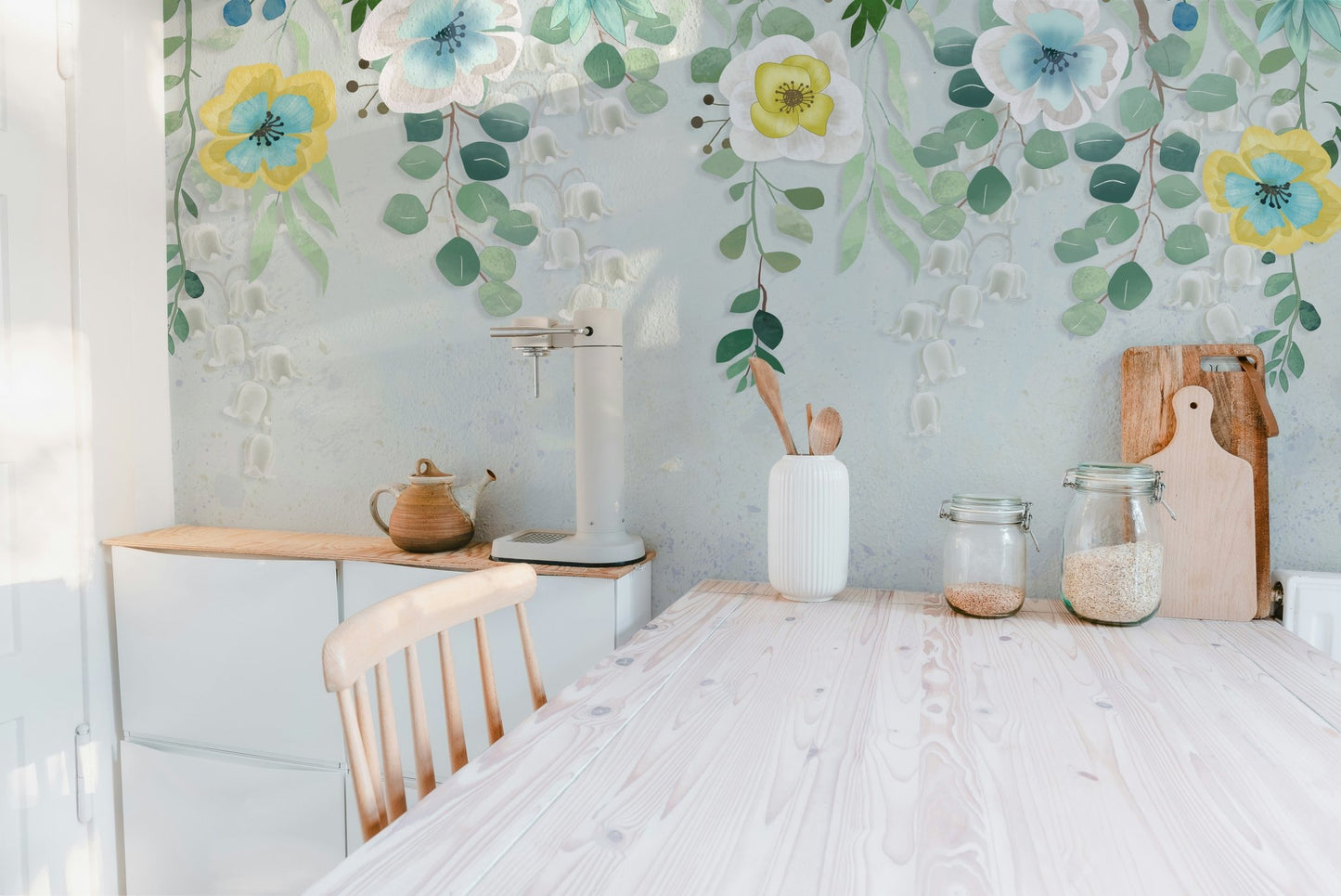 Wooden kitchen table set against a leafy botanical blossoms wall mural.