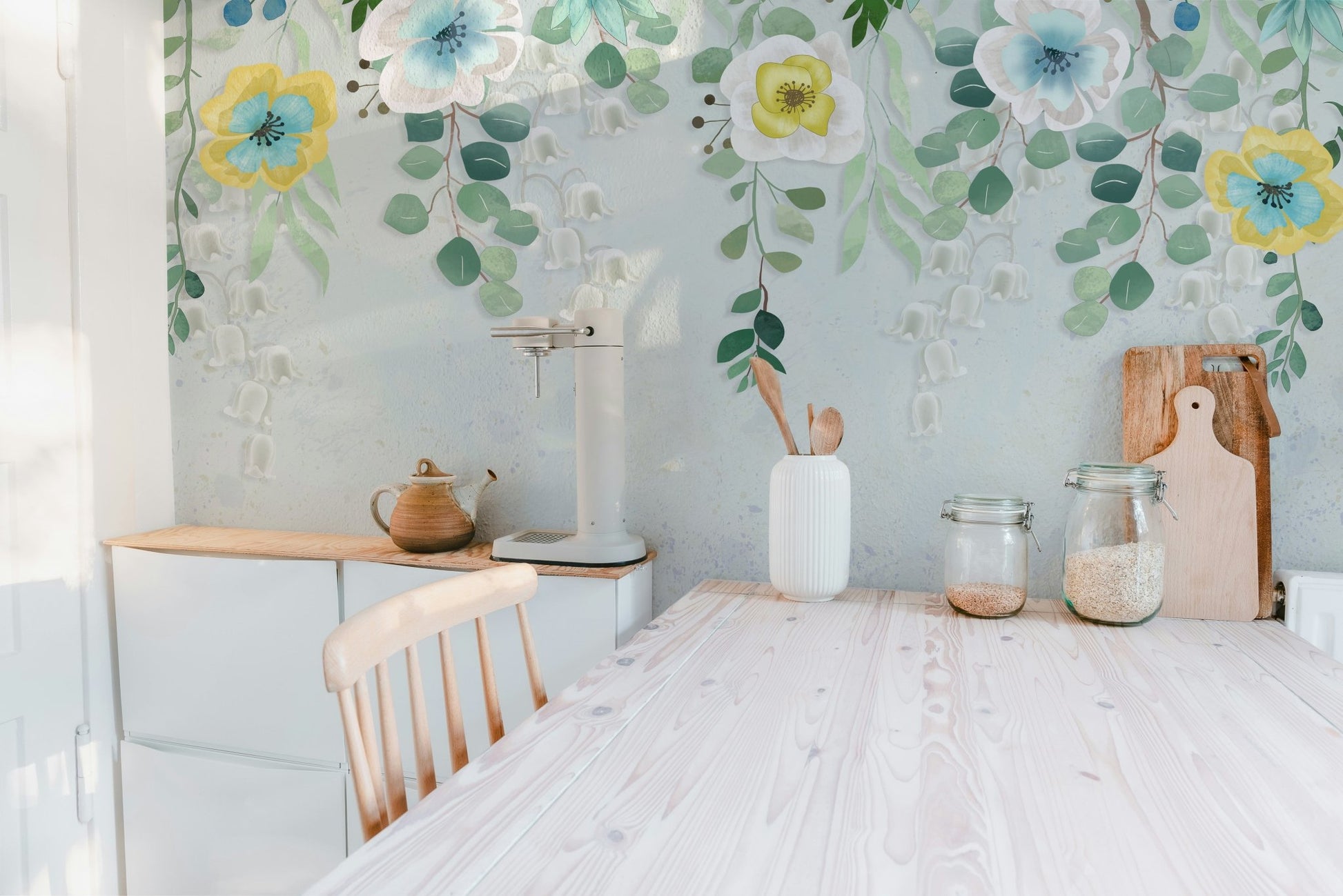 Wooden kitchen table set against a leafy botanical blossoms wall mural.