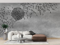Neutral tone wall mural with bird motifs in a living room with a brown ottoman.