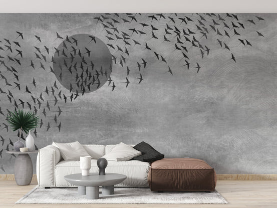 Neutral tone wall mural with bird motifs in a living room with a brown ottoman.