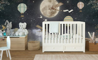 Nursery wall mural showing white crib against dark night sky with moon and balloons.