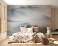 Neutral tone mountain wall mural in bedroom with light wood furniture and sunlit window.


