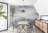 Grey foggy hills wall mural in dining room with wooden table and black chairs.