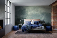 Dark green pine forest mural in a bedroom with blue bedding and dark walls.