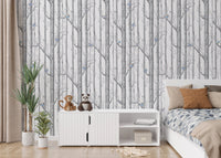 Nature themed forest wallpaper with blue bird accents in a minimalist kids bedroom.
