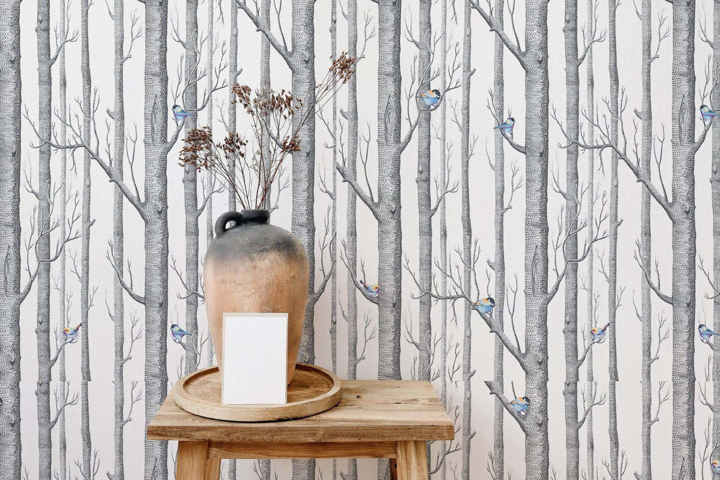 Vertical birch forest wallpaper on a feature wall behind a wooden side table and vase.
