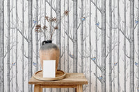 Vertical birch forest wallpaper on a feature wall behind a wooden side table and vase.