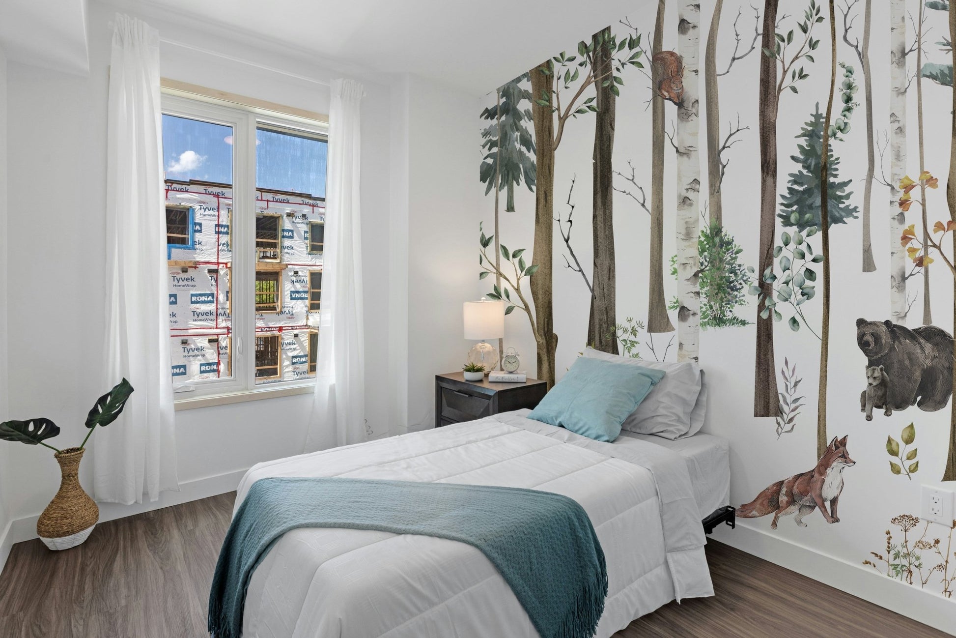 Bright bedroom with a woodland forest wall mural.