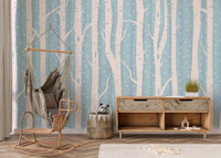 Scandinavian style forest wall mural in a playroom with a rocking chair and cabinet.