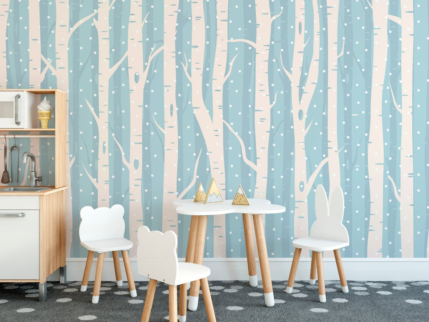 Blue and white forest wall mural in a kids dining area with small chairs and table.
