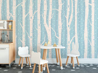 Blue and white forest wall mural in a kids dining area with small chairs and table.