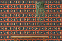 Orange and black tribal wallpaper in a room with a long wooden bench.
