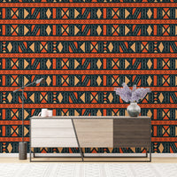 Tribal art wallpaper behind a tri-color wooden sideboard with a purple plant.