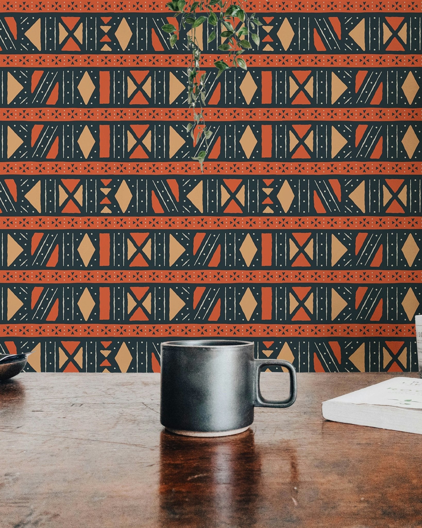 Tribal geometric wallpaper on a wall behind a dark wooden desk and coffee mug.