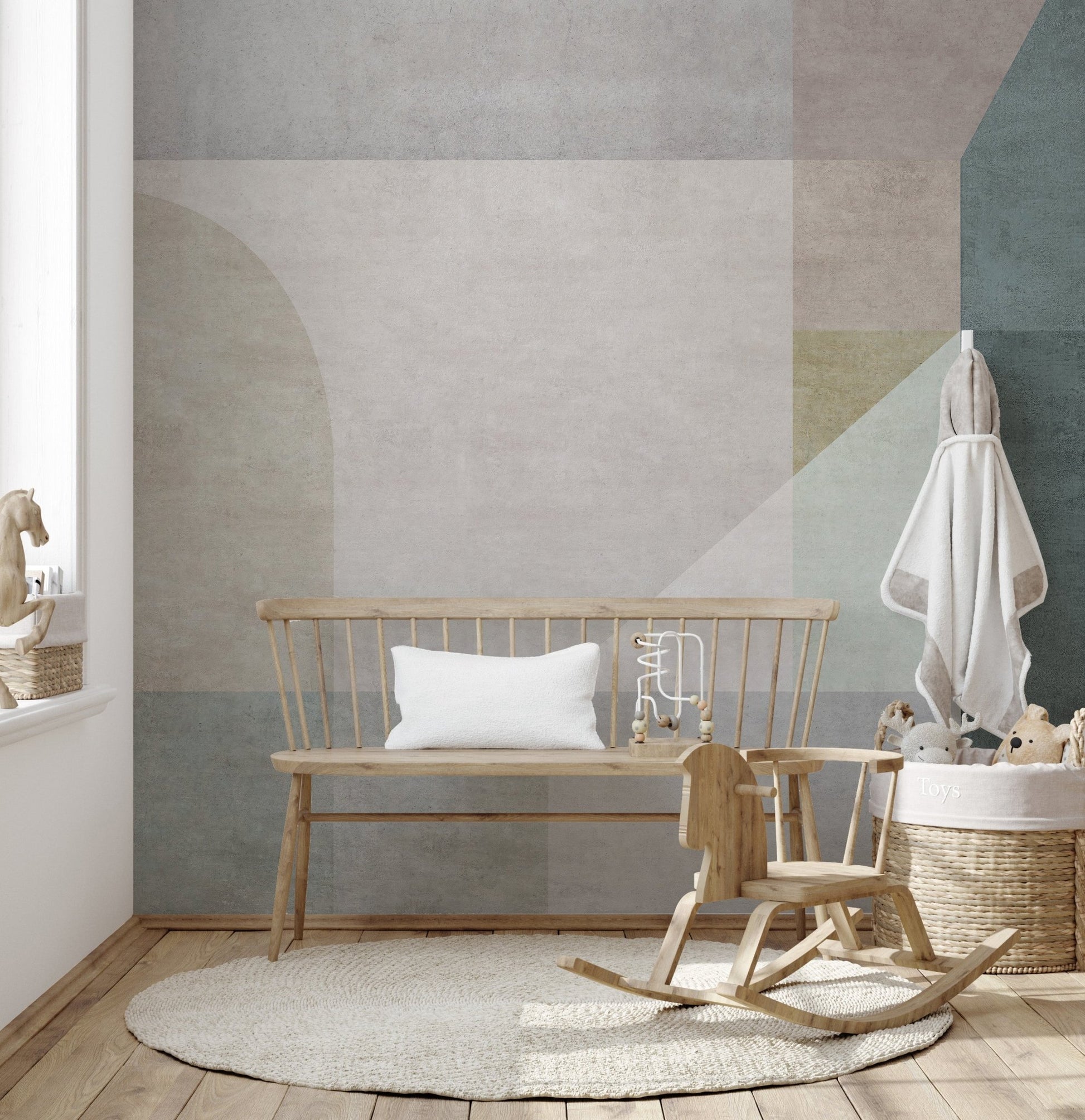 Soft colored geometric wall mural in a nursery with a wooden rocking horse.
