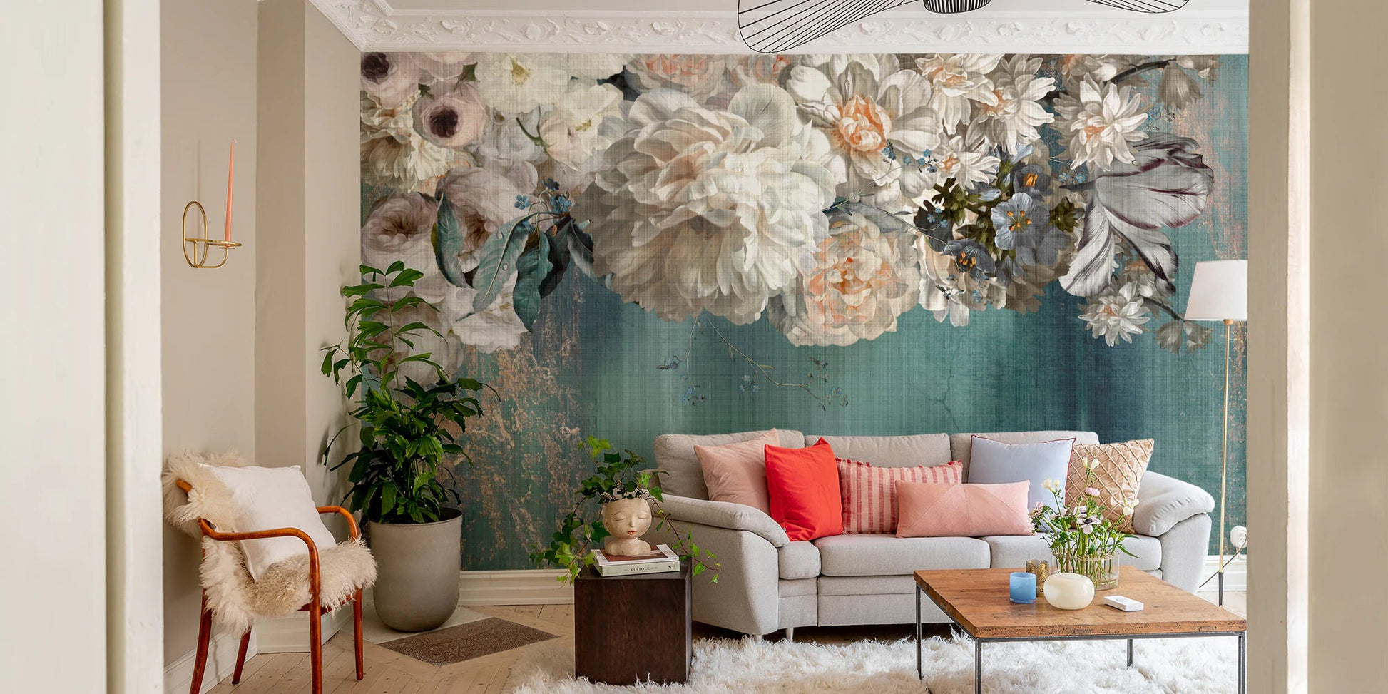 Vintage floral wall mural behind a grey sofa and indoor plants.