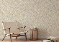 Minimalist chair and side table against a gold circle stripe wallpaper.