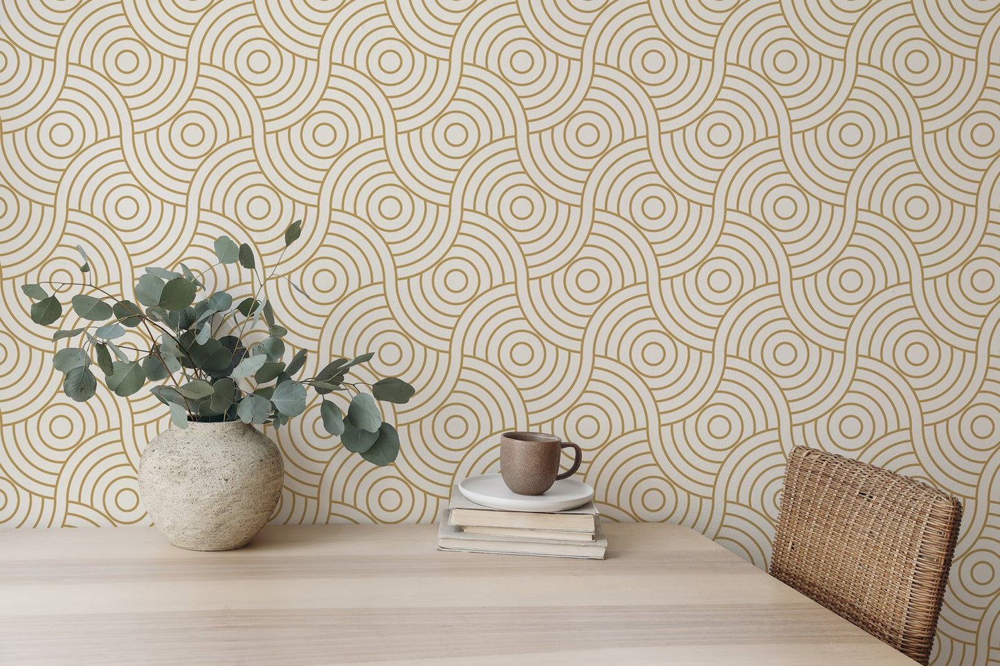 Desk area featuring gold abstract wave wallpaper with a potted plant and mug.