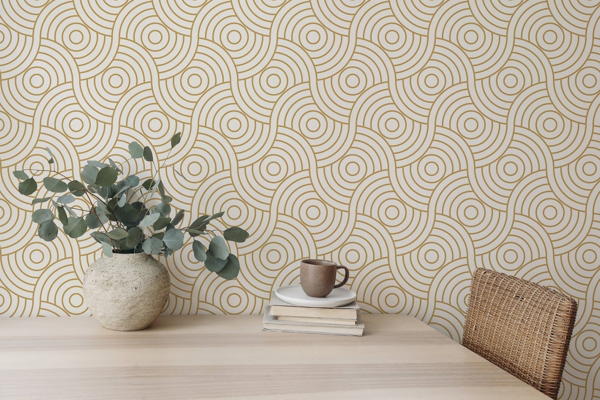 Desk area featuring gold abstract wave wallpaper with a potted plant and mug.