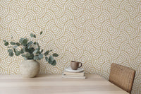 Desk area featuring gold abstract wave wallpaper with a potted plant and mug.