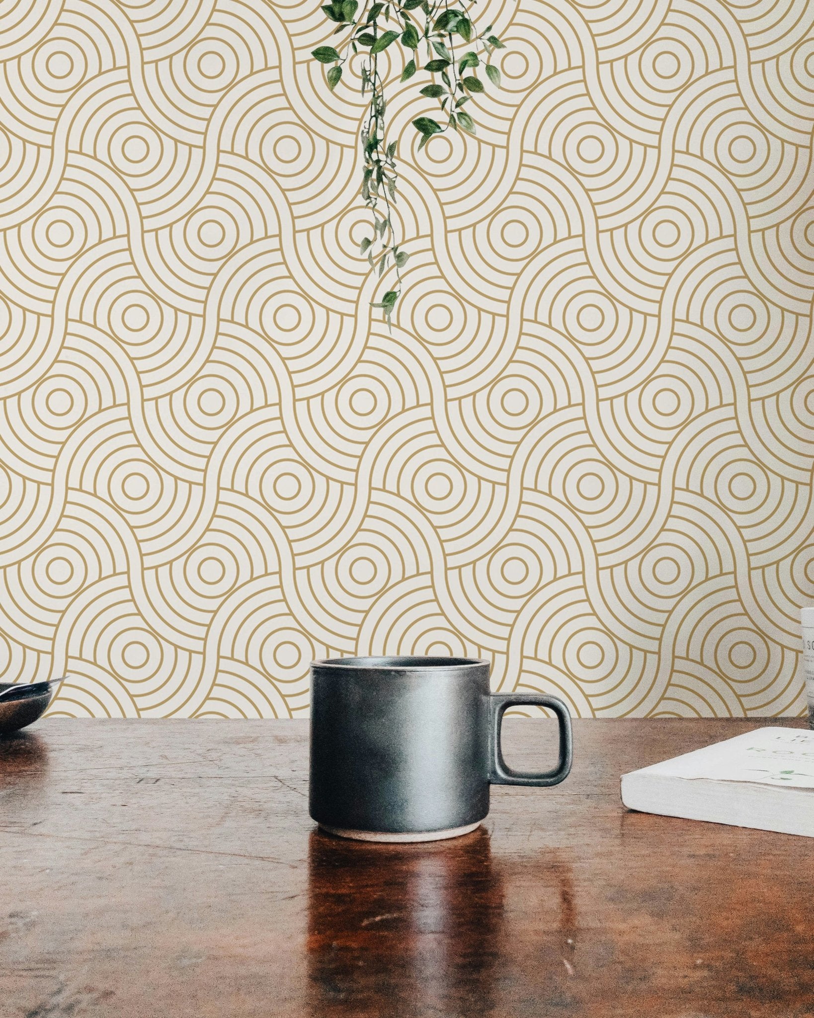 Workspace view with a black mug and gold abstract circle wallpaper backdrop.