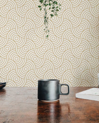 Workspace view with a black mug and gold abstract circle wallpaper backdrop.