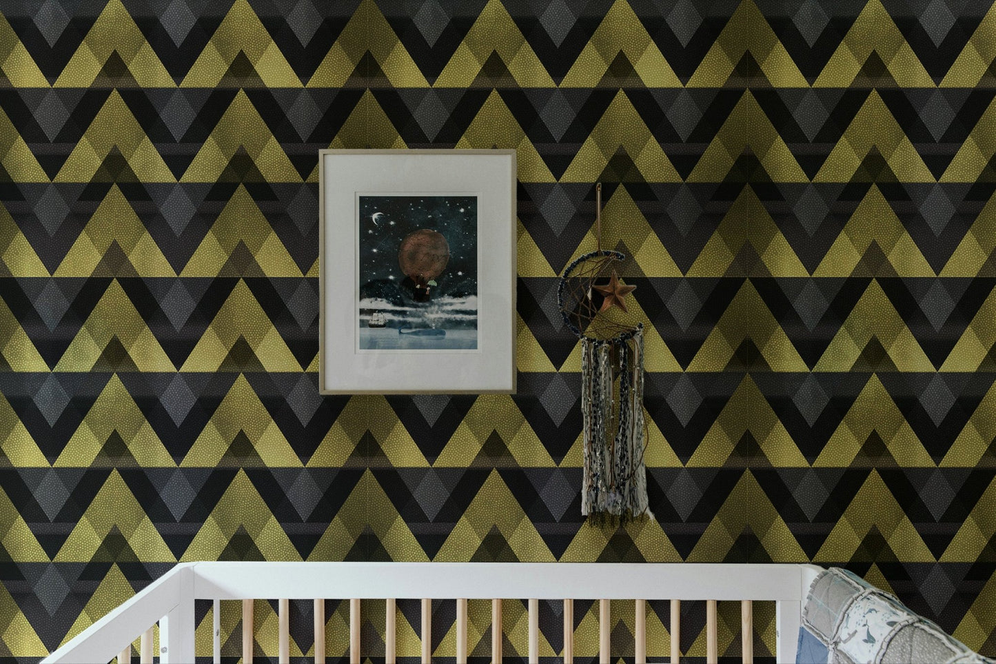 Framed art on a gold zigzag wallpaper in a nursery setting.
