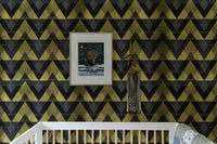 Framed art on a gold zigzag wallpaper in a nursery setting.
