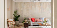 Living room wall mural with golden foliage patterns and neutral furniture.