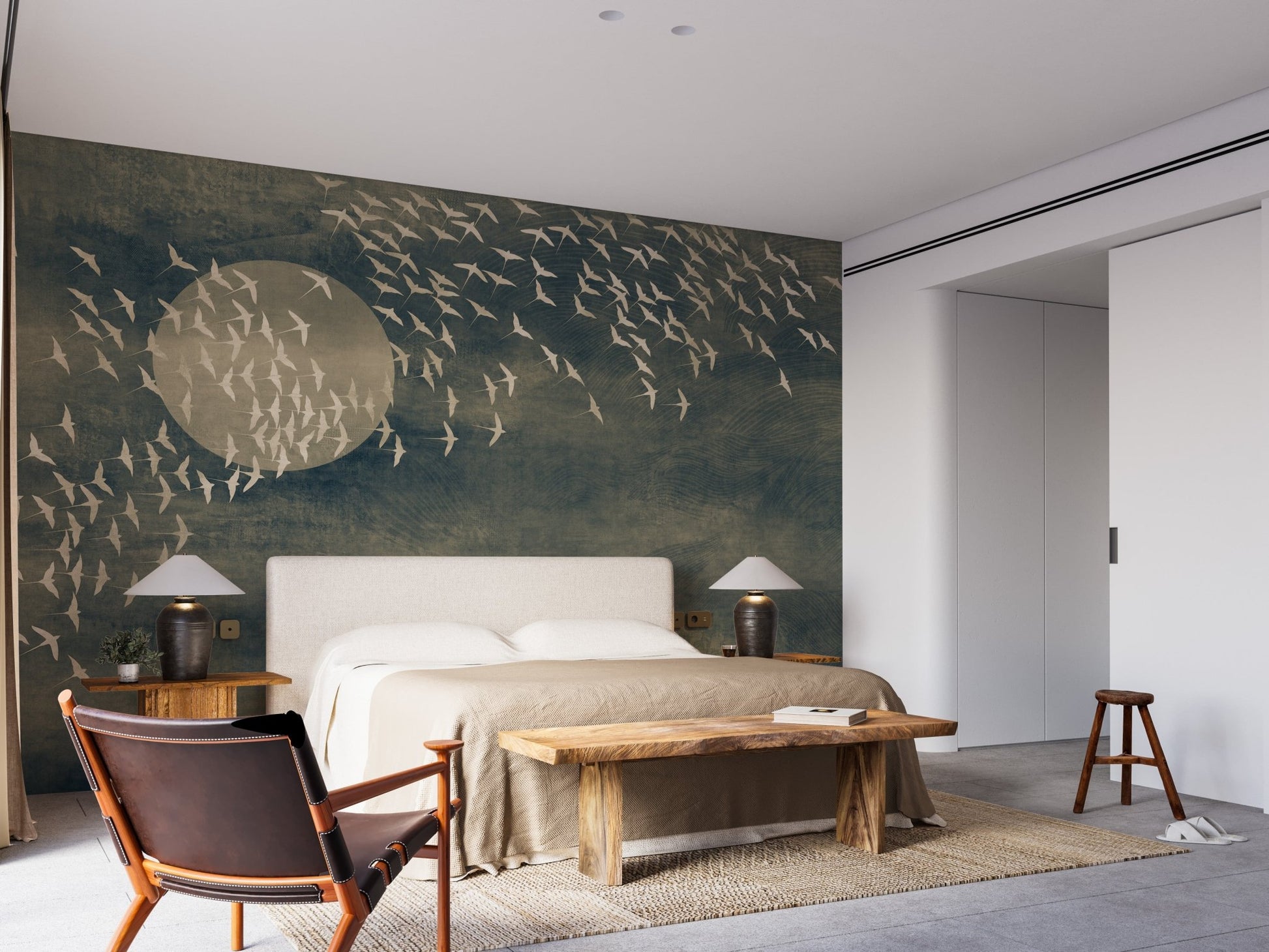 Textured dark wall mural with bird motifs in spacious bedroom with armchair.