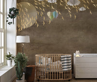 Wall mural featuring gold bird silhouettes behind a wooden crib in a nursery.