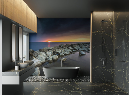 Sunset ocean wallpaper featuring rocky shoreline under a moody blue sky.