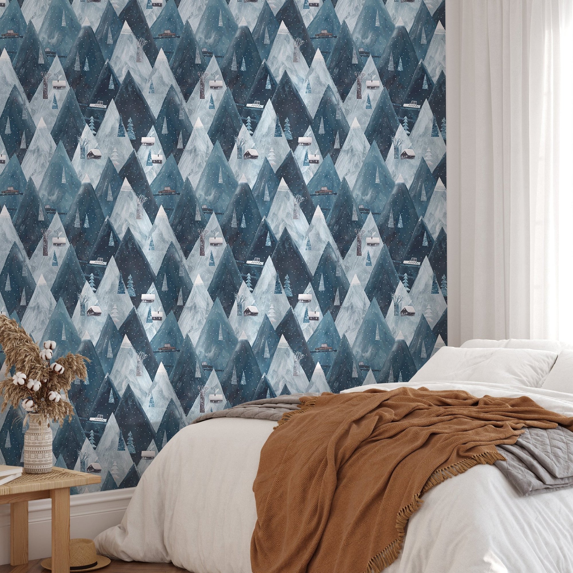 Blue gouache mountains houses scandinavian wallpaper in bedroom with brown throw.