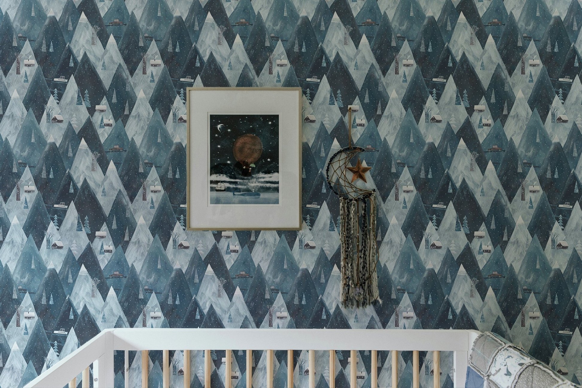 Scandinavian wallpaper with mountain and house pattern in nursery with white crib.