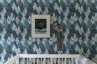 Scandinavian wallpaper with mountain and house pattern in nursery with white crib.