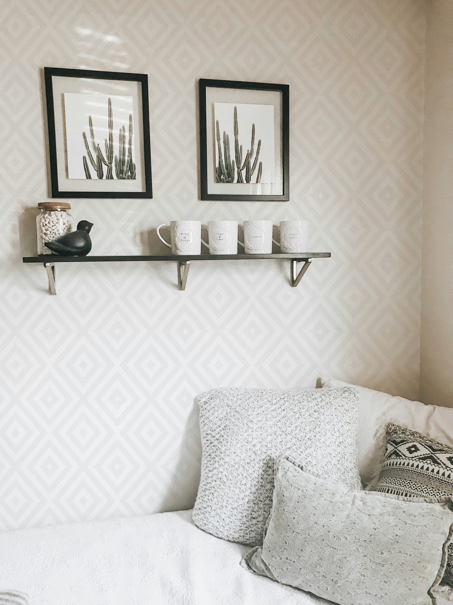Decorative shelving with black frames on a light gray diamond wallpaper.