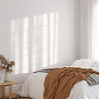 Sunlit bedroom featuring a textured gray geometric wallpaper behind the bed.