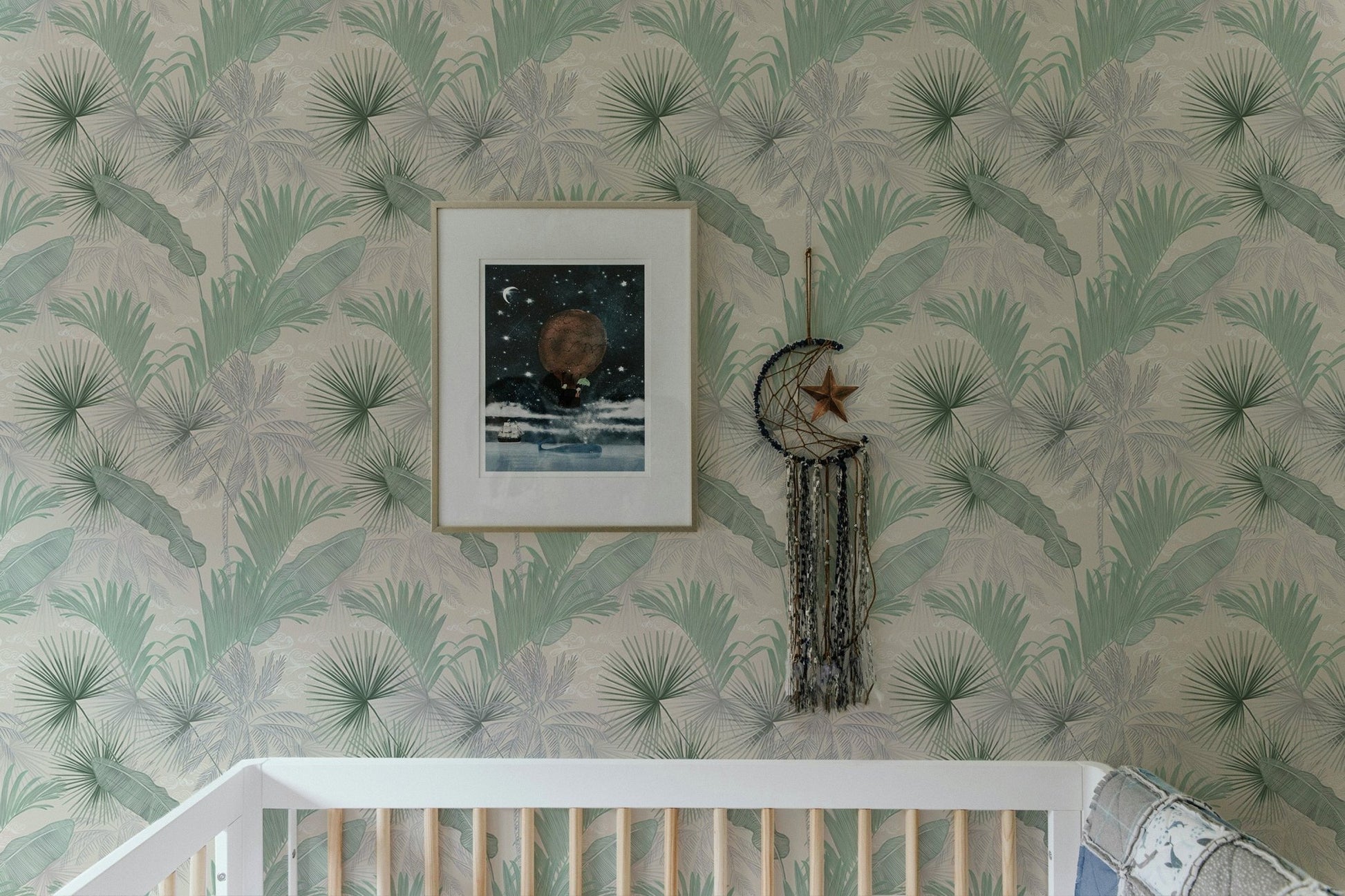 Banana leaf wallpaper pattern above a white crib in a nursery.
