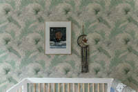 Banana leaf wallpaper pattern above a white crib in a nursery.